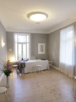 Der Atemraum bei einer Einzelstunde Lichtdurchfluteter Behandlungsraum im Altbau mit einer Liege und frischen Blumen